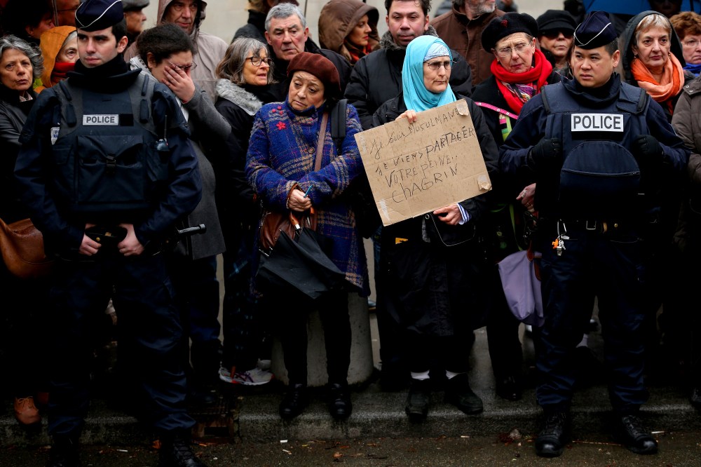 Amid tight security, a woman holds up a sign saying 'I am a Muslim. I come to share your grief' as members of the public pay respects at the funeral of Charlie Hebdo a cartoonist on Jan. 15, 2015 in Paris, France.  (Photo by Christopher Furlong/Getty)