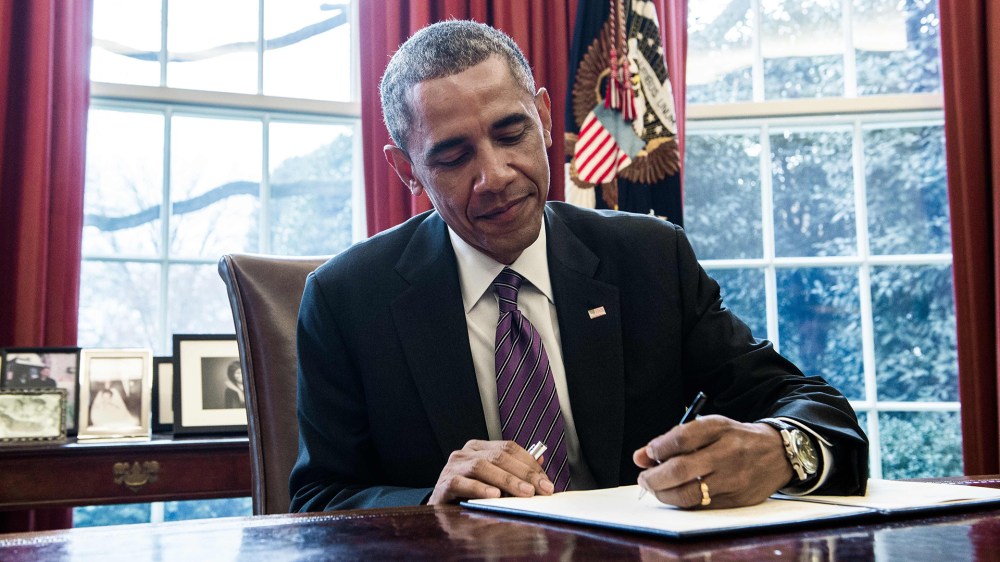 President Barack Obama signs a presidential memorandum in the Oval Office of the White House in Washington, D.C., on Jan. 15, 2015. (Photo by Nicholas Kamm/AFP/Getty)
