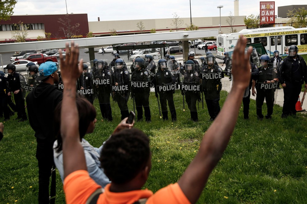 A protestors confronts Baltimore Police officers with his hands up near Mondawmin Mall on April 27, 2015 in Baltimore, Md.