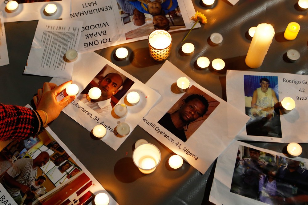 A woman places a candle on top of pictures of the prisoners to be executed in Indonesia, during a vigil at Martin Place on April 28, 2015 in Sydney, Australia. (Photo by Daniel Munoz/Getty)
