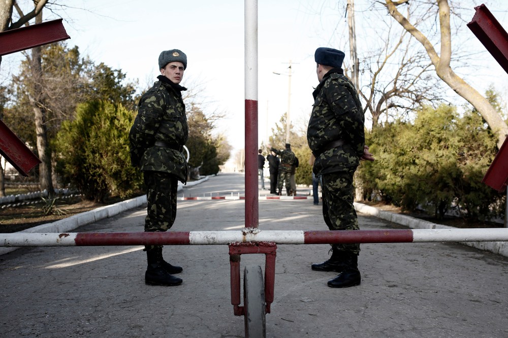 Ukrainian soldiers wait in front of the main entrance of the barracks at the Ukrainian military base in Eupatoria, taken under control by Russian army forces in Crimea on March 5, 2014.
