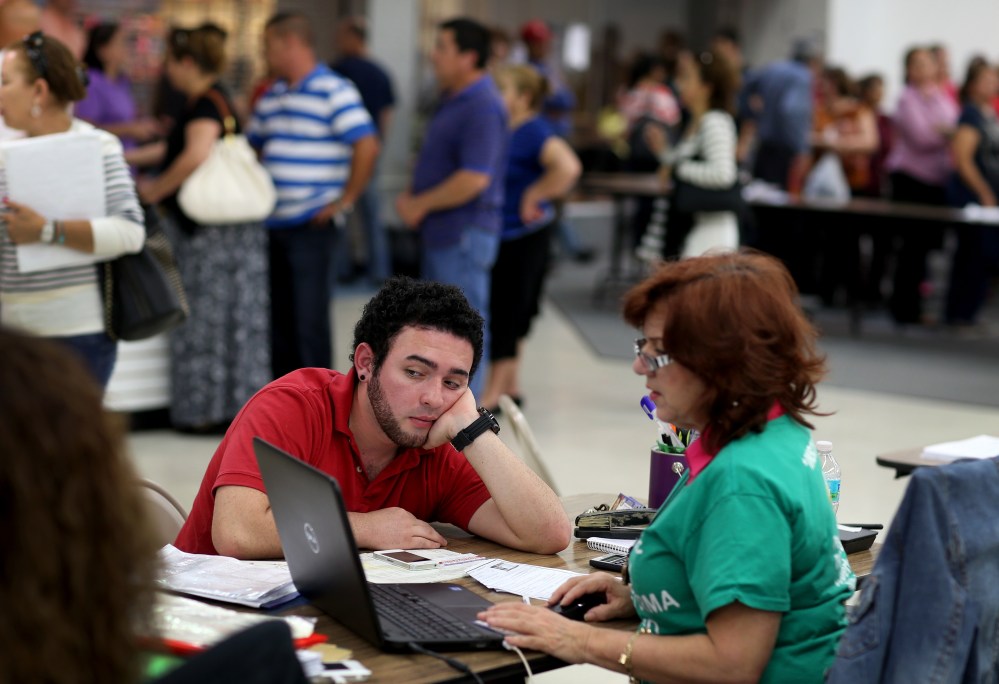 Andres Cuartas sits with an agent with Sunshine Life and Health Advisors as he purchases a health insurance plan under Obamacare in Miami, March 31, 2014.