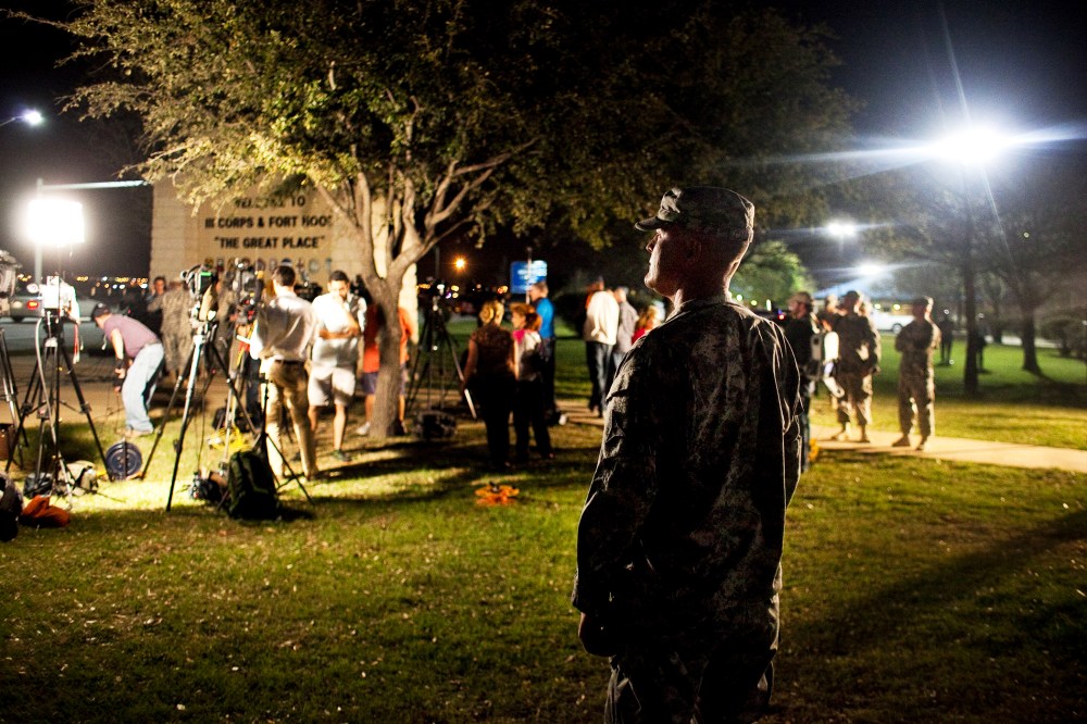 A soldier watches over media as they prepare for a press conference about the shooting at Fort Hood, April 2, 2014.