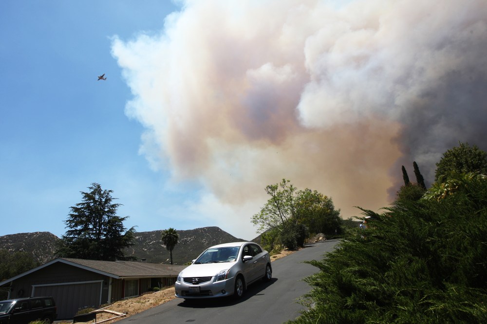Smoke rises as the southeast flank of the Cocos fire bears down on houses near Del Dios Highway on May 15, 2014 near San Marcos, California.