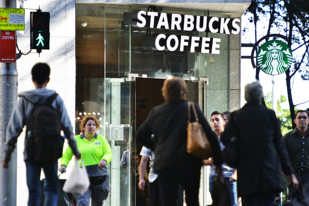 Pedestrians cross a street in front of a Starbucks coffee house in Sydney on May 28, 2014.