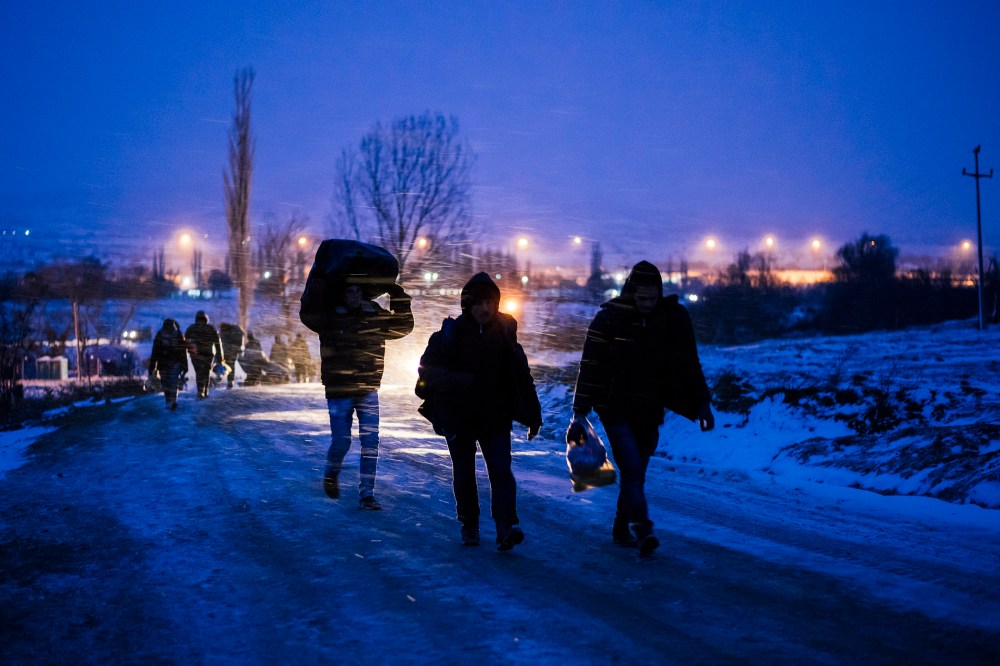 Migrants and refugees walk on a snow covered street after crossing the Macedonian border into Serbia near the village of Miratovac on Jan. 17, 2016. (Photo by Dimitar Dilkoff/AFP/Getty)