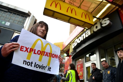 A woman carries a sign past a McDonald's on East 125th Street and Lexington Avenue in Harlem during a protest by fast food workers and supporters for higher wages April 4, 2013 in New York. (STAN HONDA/AFP/Getty Images)