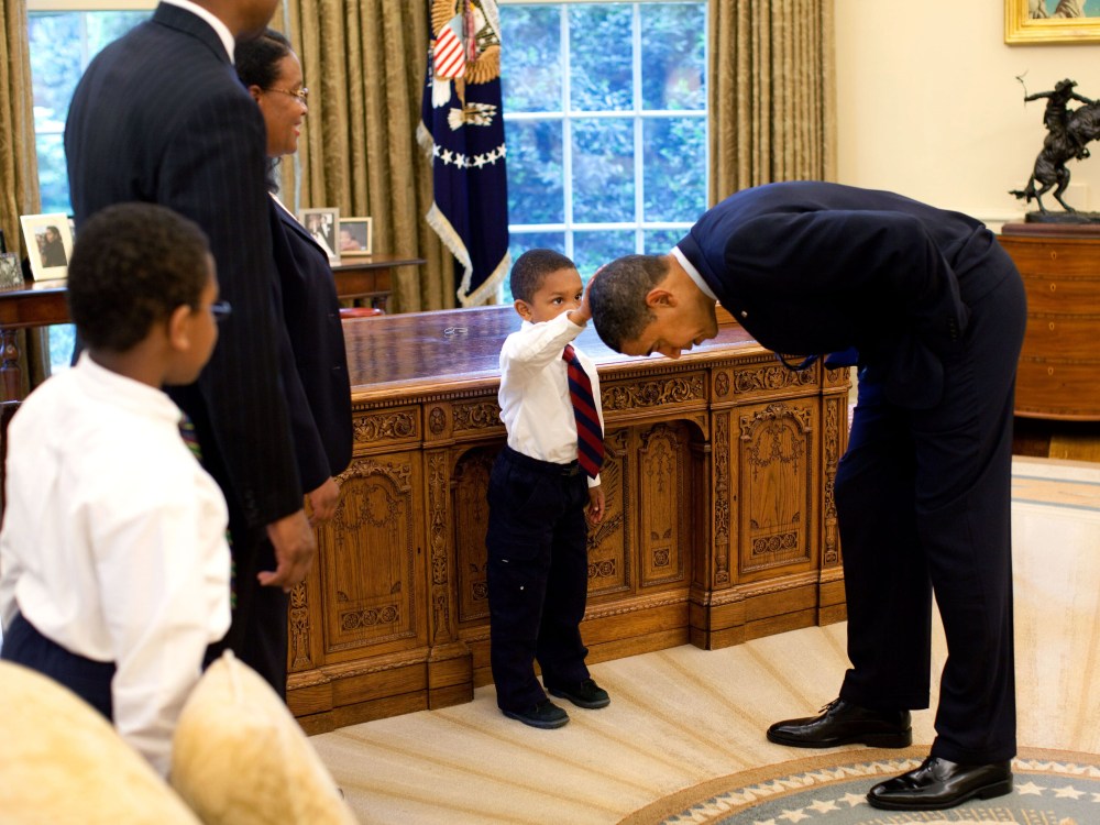 File Photo: In this handout from the The White House, U.S. President Barack Obama bends over so the son of a White House staff member can pat his head during a visit to the Oval Office May 8, 2009 in Washington, DC.  (Photo by Pete Souza/The White...
