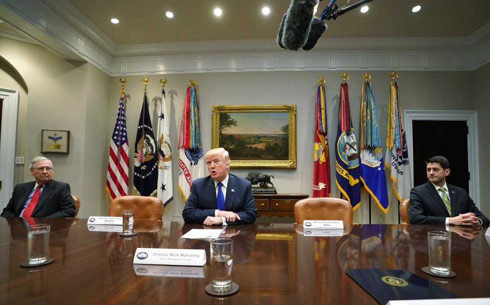 U.S. President Donald Trump speaks to the media as Senate Majority Leader Mitch McConnell (L), R-KY, and Speaker of the House Paul Ryan, R-WI, look on during a meeting with congressional leadership in the Roosevelt Room at the White House on November 28,