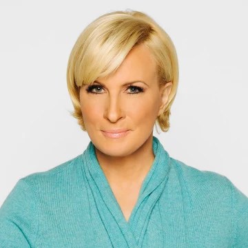 Mika Brzezinski in a teal top on a gray background.