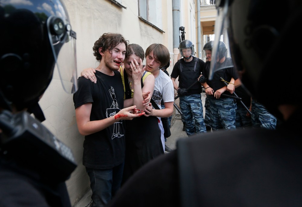 Riot police guard gay rights activists who were beaten by anti-gay protesters at an authorized gay rights rally in St. Petersburg, Russia on June 29, 2013