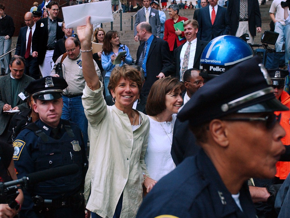 Hillary Goodridge holds up an envelope containing her marriage license as she leaves Boston City Hall with her partner Julie under a police escort in Boston, Monday May 17, 2004.