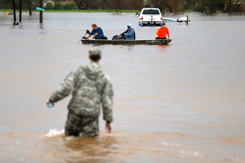 A Louisiana National Guardsman wades through water as residents are evacuated by boat through rising floodwaters in Bossier Parish, La., March 10, 2016. (Photo by Gerald Herbert/AP)