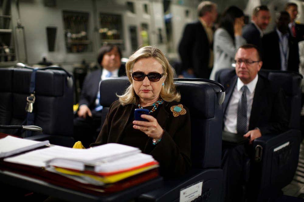 Then-Secretary of State Hillary Rodham Clinton checks her Blackberry from a desk inside a C-17 military plane upon her departure from Malta, in the Mediterranean Sea, bound for Tripoli, Libya on Oct. 18, 2011. (Photo by Kevin Lamarque/Pool/AP)