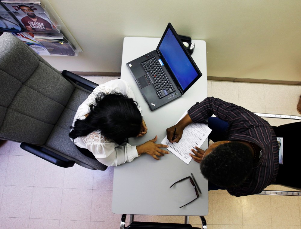 Clinical applications counselor Rachael Richardson works with Louis Peters at the Henry J. Austin Health Center, in Trenton, N.J., as he and others fill out papers to sign up for new plans through a health insurance exchange, Oct. 1, 2013.