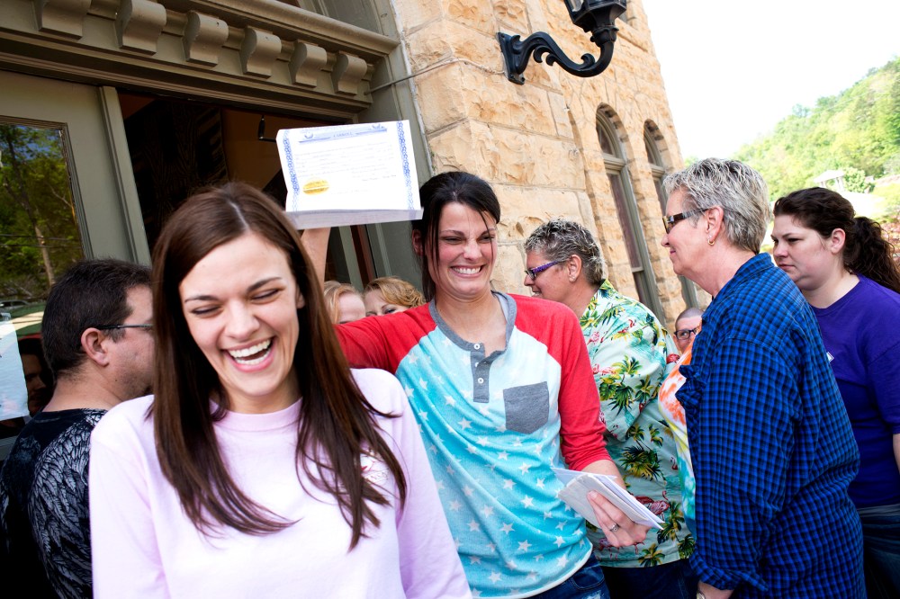 Kristin Seaton, of Jacksonville, Ark., holds up her marriage license as she leaves the Carroll County Courthouse in Eureka Springs, Ark., with her partner, Jennifer Rambo, May 10, 2014.