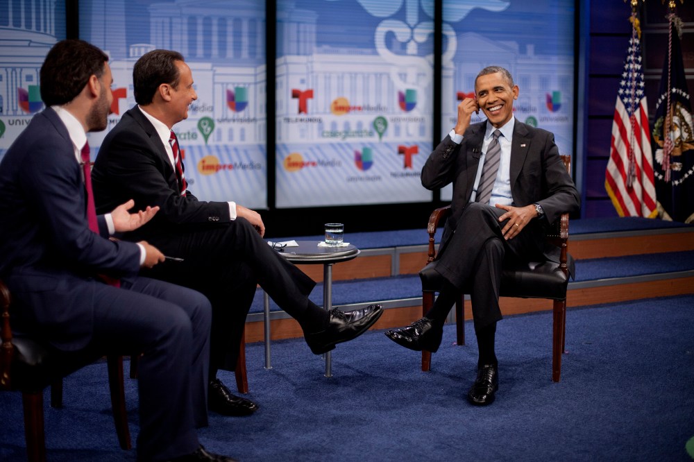 President Barack Obama adjusts his earpiece during a town hall event with television hosts Jose Diaz Balart and Enrique Acevedo, far left, at the Newseum in Washington, on March 6, 2014.