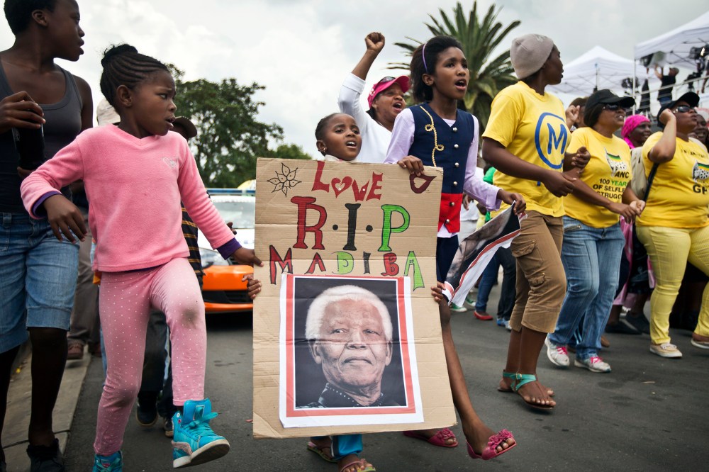 A young girl marches with others to celebrate Nelson Mandela's life, in the street outside his old house in Soweto, Johannesburg, South Africa, Dec. 6, 2013.