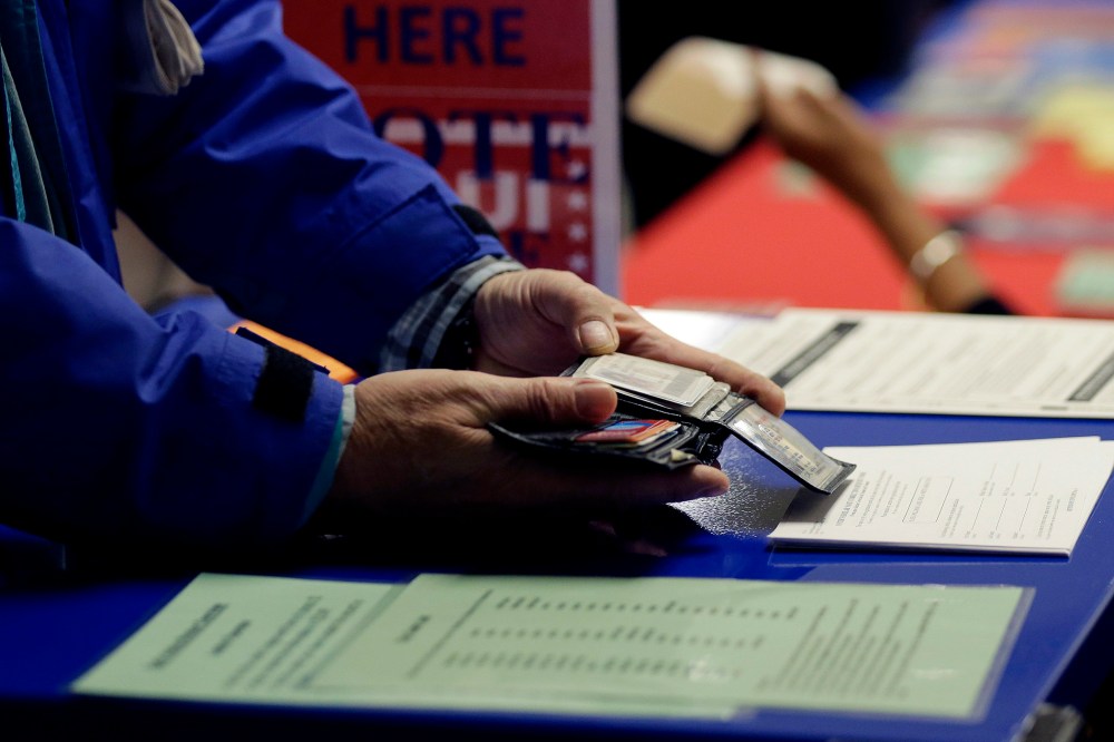 A voter shows his photo identification to an election official at an early voting polling site, in Austin, Texas on Feb. 26, 2014.