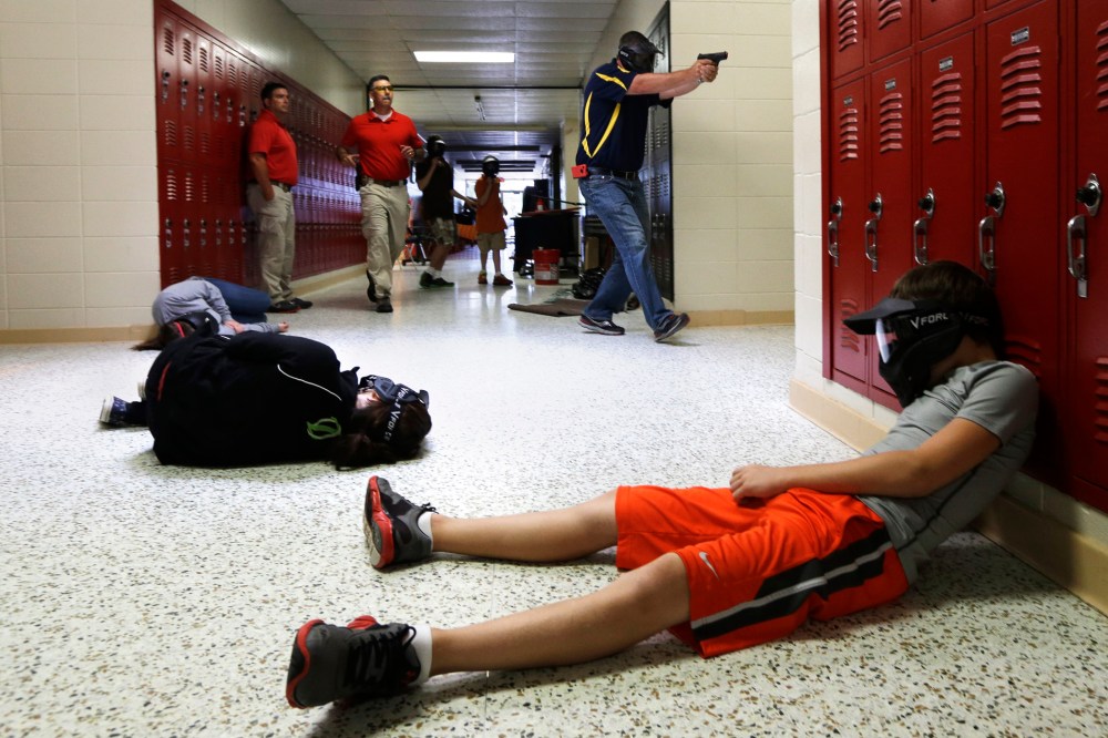 A Clarksville Schools faculty member carries an air-powered practice handgun during a training exercise in Clarksville, Ark., July 11, 2013.