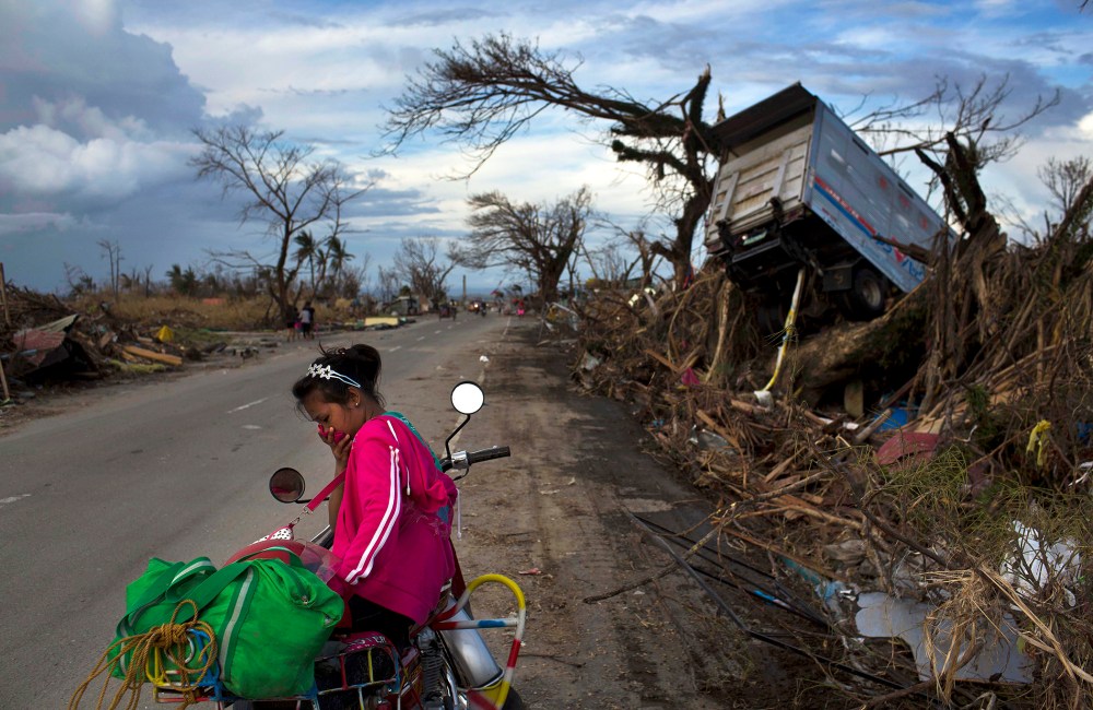 A woman rests on a roadside with her family's belongings near the Typhoon Haiyan ravaged town of Tacloban