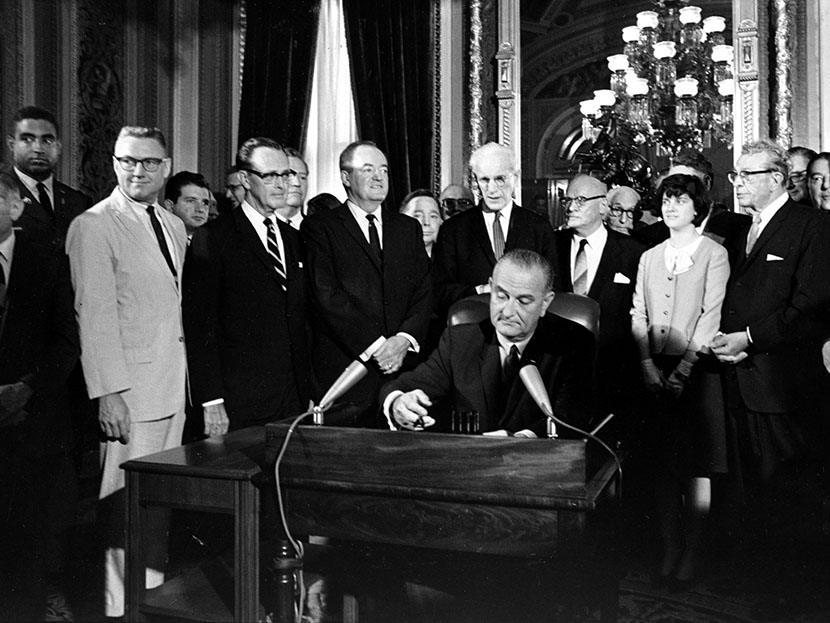 In this Aug. 6, 1965, photo, President Lyndon Baines Johnson signs the Voting Rights Act of 1965 in a ceremony in the President's Room near the Senate Chambers on Capitol Hill in Washington.   (Photo by AP)