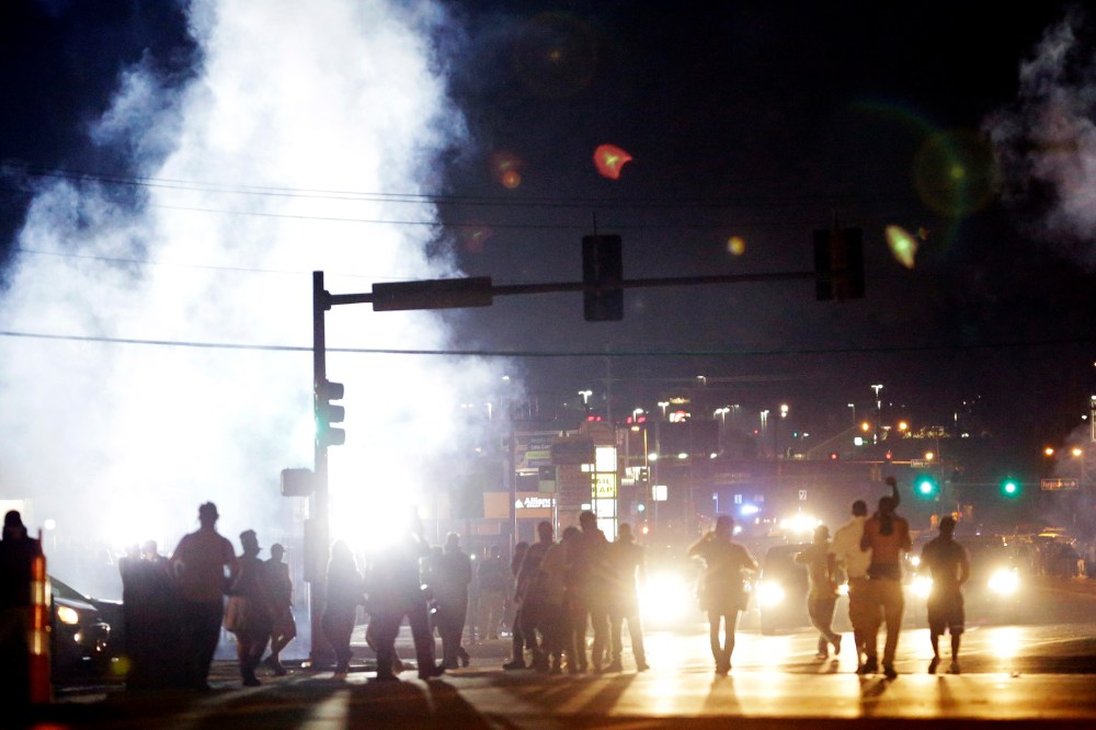 Protesters walk through a cloud of tear gas Monday, Aug. 18, 2014, in Ferguson, Mo.