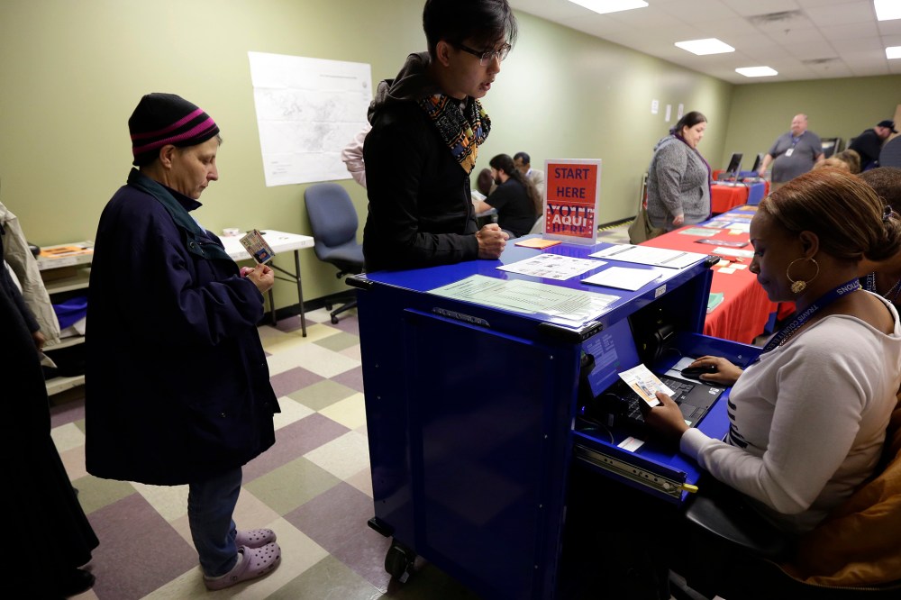 Voters stand in line to have an election official check their photo identification at an early voting polling site, in Austin, Texas on Feb. 25, 2014.