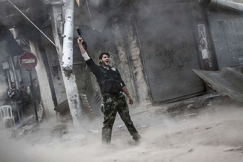 A rebel fighter claims for victory after he fires a shoulder-fired missile toward a building where Syrian troops loyal to President Bashar Assad are hiding while they attempt to gain terrain against the rebels during heavy clashes in the Jedida...