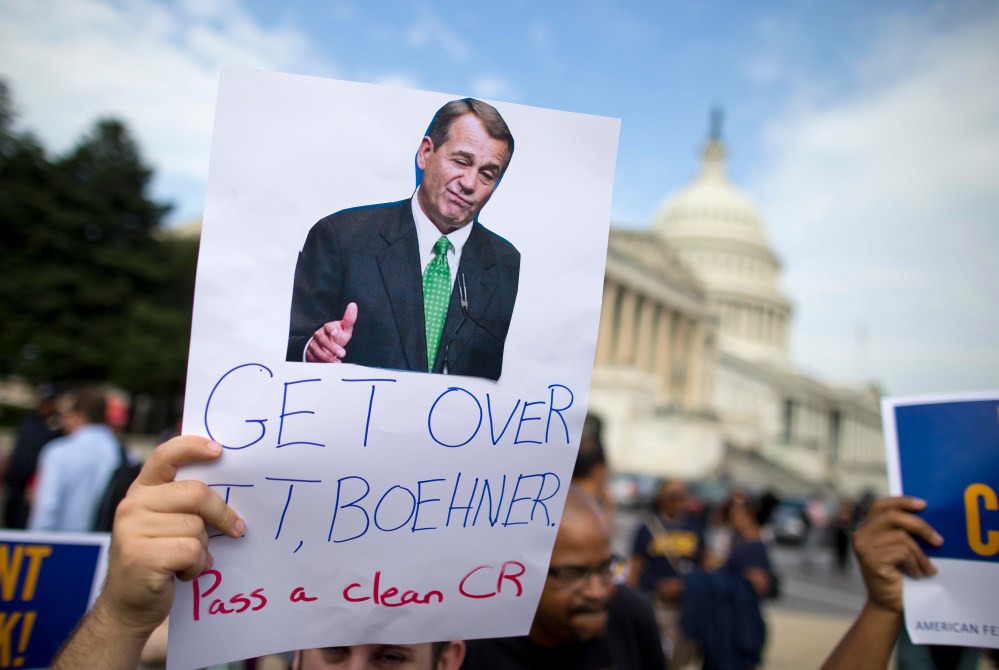 A protestor holds a sign calling on House Speaker John Boehner to pass a clean continuing budget resolution during an event on Capitol Hill in Washington, Friday, Oct. 4, 2013.