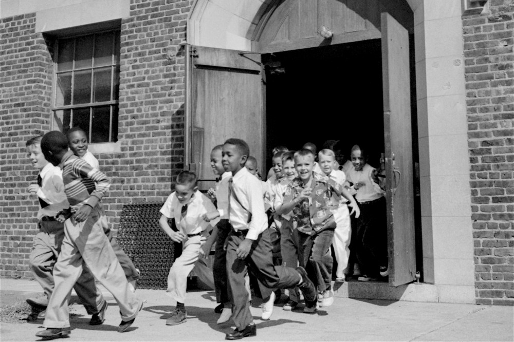 Black and white fourth graders at St. Martin School, Washington, DC, dash for the playground at recess, September 17, 1954.
