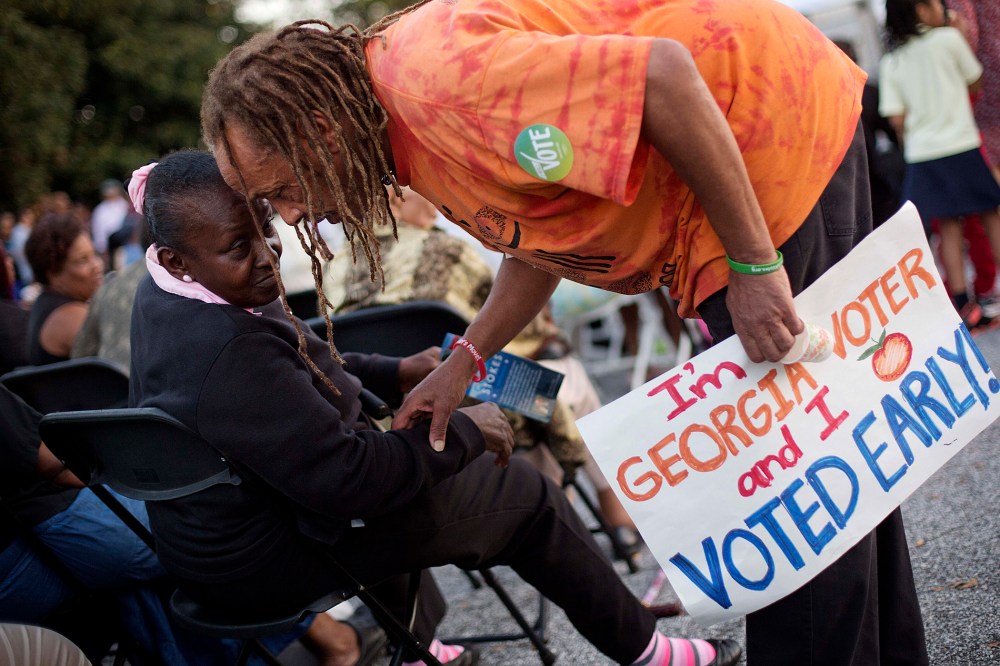 Alvin Dollar, of Decatur, right, carries a sign proclaiming he voted early as he talks with Dianna Green, of Atlanta at a Democratic rally encouraging early voting before U.S. Senate candidate Michelle Nunn takes the stage, on Oct. 27, 2014, in Decatur.