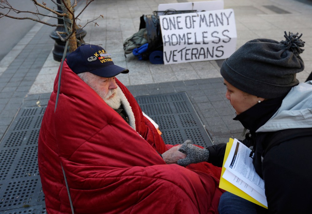 Homeless Korean War veteran Thomas Moore, 79, left, speaks with Boston Health Care for the Homeless street team outreach coordinator Romeena Lee on a sidewalk in Boston, Nov. 20, 2013.