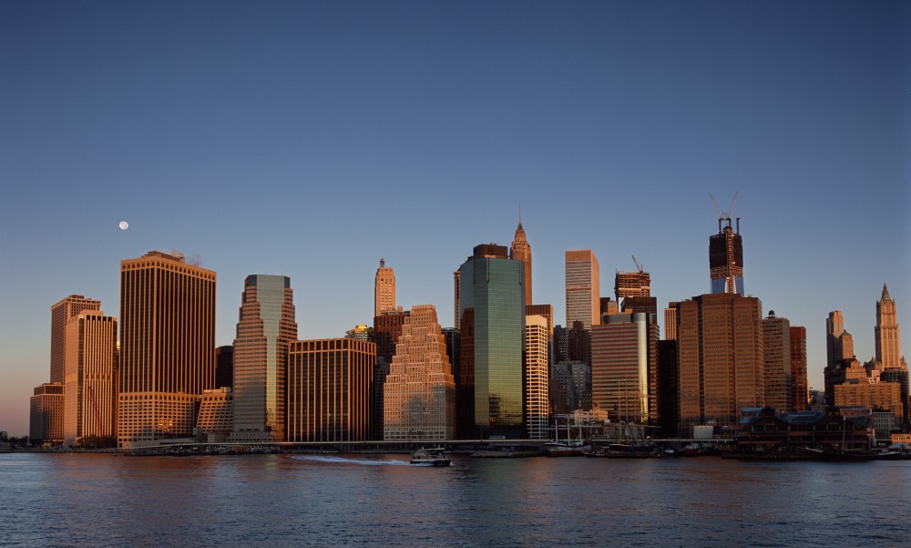 A nearly full moon hangs above the lower Manhattan skyline shortly after dawn on Monday, Oct. 1, 2012, in New York, as seen from Brooklyn Bridge Park. One World Trade Center rises at background right.