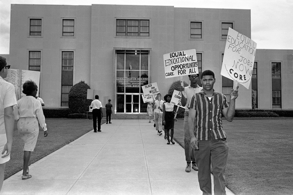 Members of CORE march in front of the administration building of the Dallas Independent School District carrying placards in Dallas, Texas on Aug. 26, 1964.