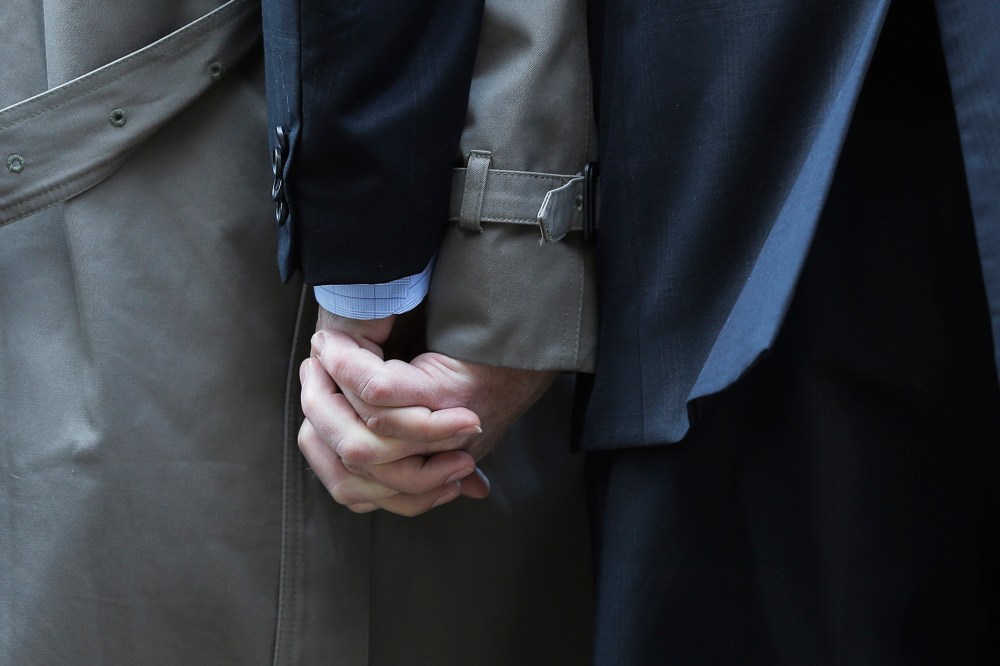 Mark Phariss, left, clutches the hand of partner Victor Holmes, right, as they talk to the media outside the U.S. Federal Courthouse in San Antonio, Texas, Feb. 12, 2014.