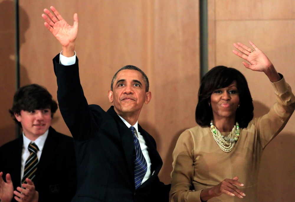 US President Barack Obama, left, waves while walking with First Lady Michelle Obama after he delivered a keynote address ahead of the G-8 summit at Waterfront Hall in Belfast, Northern Ireland on Monday, June 17, 2013. (AP Photo/Peter Morrison)