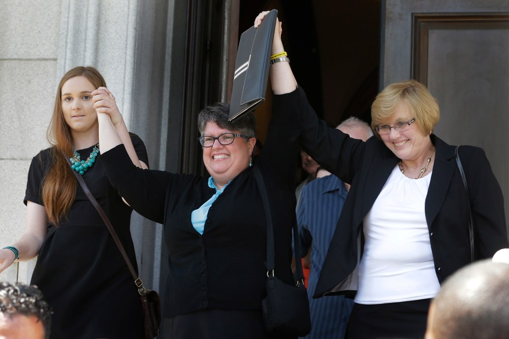 Plantiffs in the federal suit over Virginia's ban on gay marriage, Emily Schall-Townley, left, Carol Schall, center, and Mary Townley, raise their arms after a hearing on Virginia's same sex-marriage ban in Richmond, Va., on May 13, 2014.