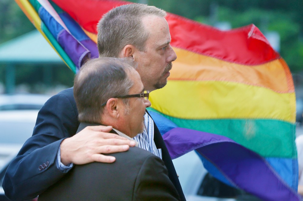 In this photo taken May 12, 2014, Shon DeArmon, top, and his partner James Porter carry a flag in support of the county issuing marriage licenses for same-sex couples at the Pulaski County Courthouse in Little Rock, Ark. (Photo by Danny Johnston/AP)