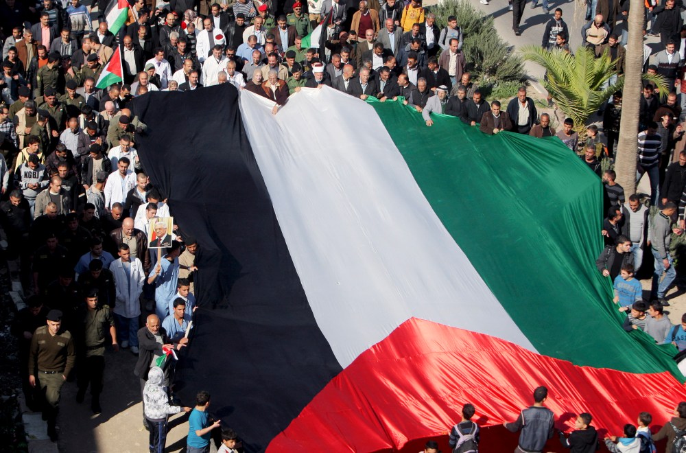 People hold a giant Palestinian flag during a rally in support of the Palestinian UN bid for observer state status, in the West Bank town of Jenin, Thursday, Nov. 29, 2012. The Palestinians are certain to win U.N. recognition as a state on Thursday but...