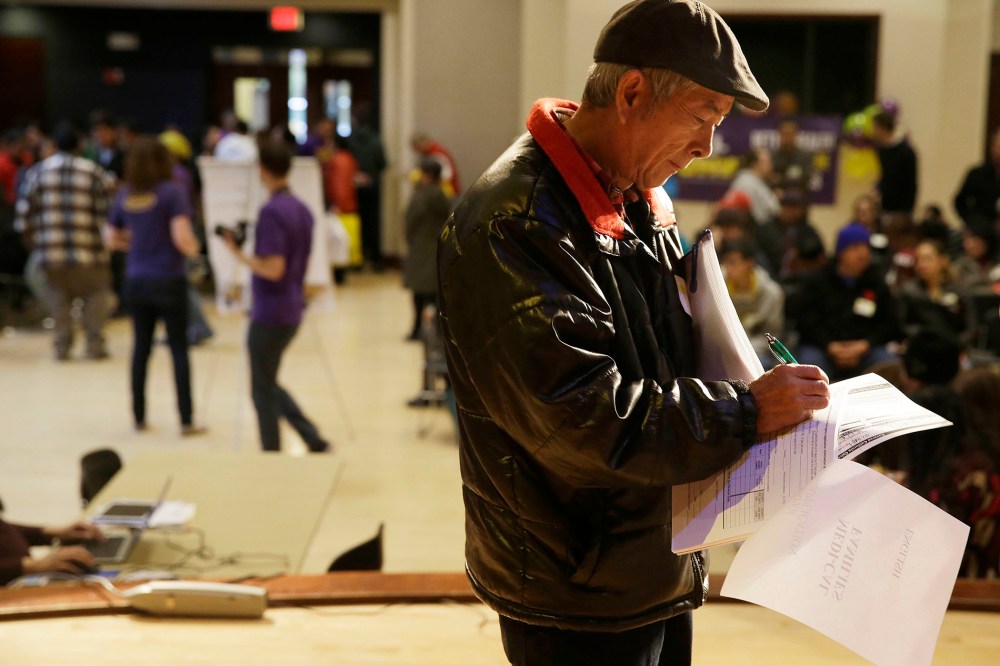 Jian Feng Liu, 57, of Fremont, Calif., finishes filling out his application form during a health care enrollment event at the Oakland Asian Cultural Center on March 31, 2014, in Oakland, Calif.