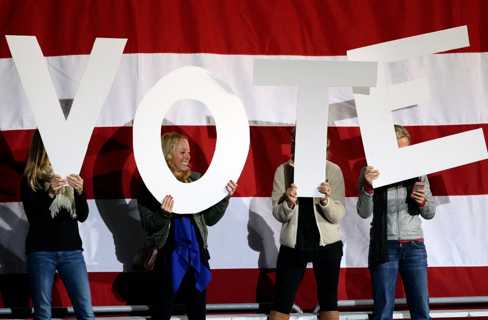 Women hold up signs spelling "vote" on a stage being prepared for a speech by President Barack Obama at a campaign rally at the Community College of Aurora, in Denver, Sunday, Nov. 4, 2012. (AP Photo/Brennan Linsley)