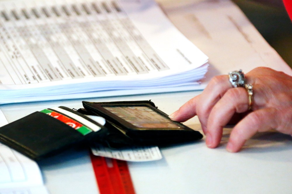 A Madison County election worker checks a voter's identification against a voting poll list before allowing him to vote in the party primary in Madison, Miss., June 3, 2014.