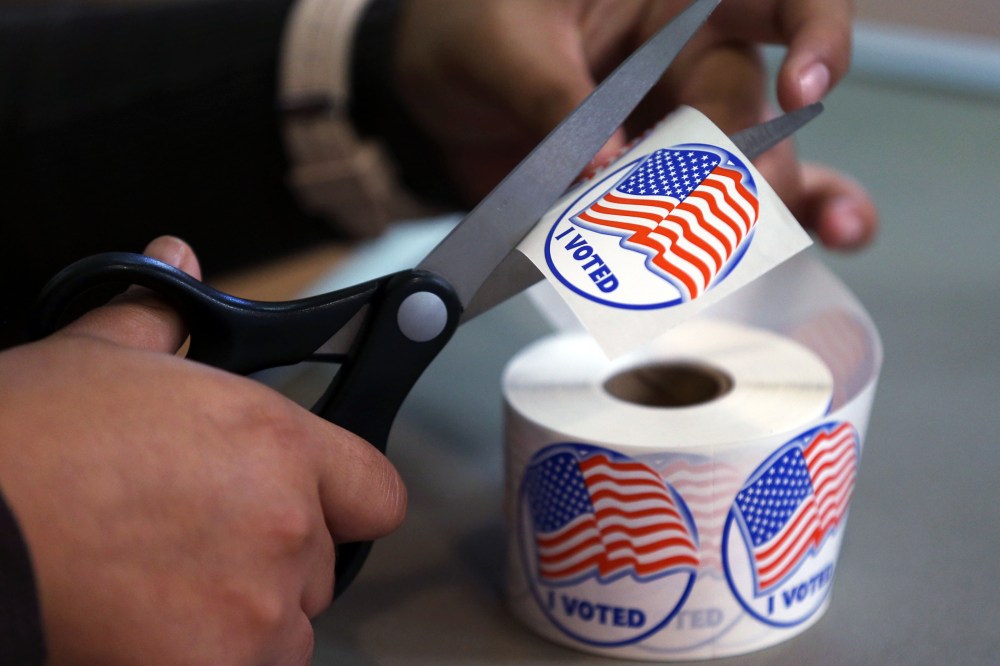 A volunteer hands out stickers to voters in Carson City, Nev., on Nov. 4, 2014. (Photo by Cathleen Allison/AP)