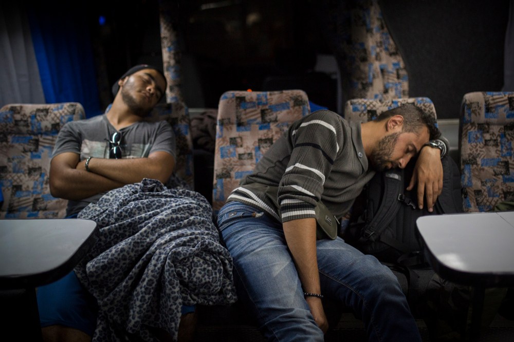 Mohammed al-Haj, right, and his friend Abdul-Rahman Babelly sleep on a bus traveling from Presevo, in southern Serbia, to the capital, Belgrade, their next stop en route to the Hungarian bordery, Sep. 12, 2015. (Photo by Santi Palacios/AP)