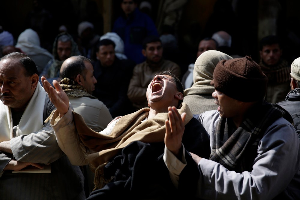 Egyptian Coptic men mourn for 21 Coptic Egyptian men killed by Islamic State militants in Libya, at the Virgin Mary Church in the village of el-Aour, 135 miles south of Cairo, Egypt on Feb. 16, 2015. (Photo by Hassan Ammar/AP)