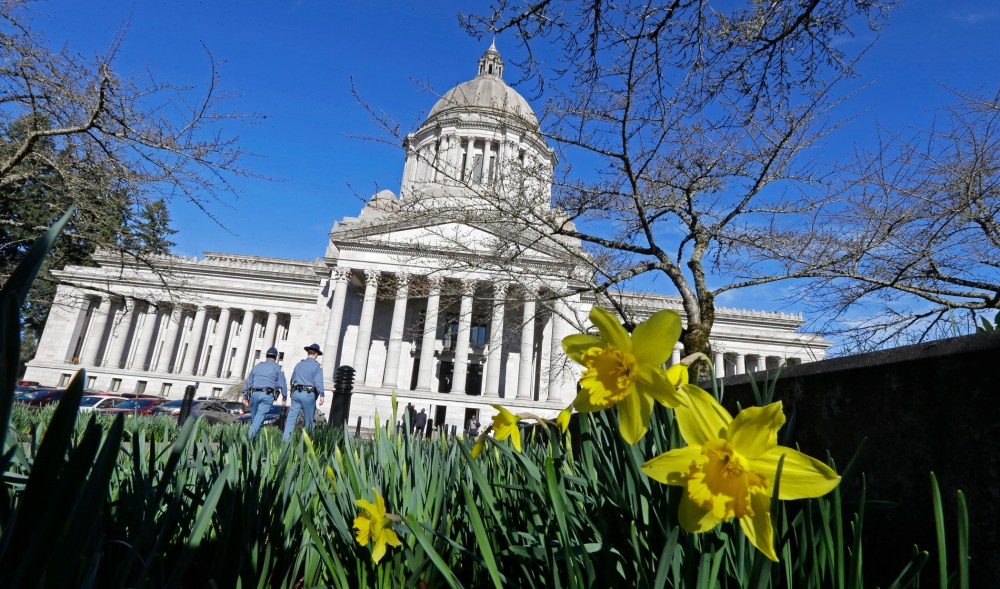 Early daffodils bloom as two Washington State Patrol troopers walk toward the U.S. Capitol, Feb. 17, 2015, in Olympia, Washington. (Photo by Ted S. Warren/AP)
