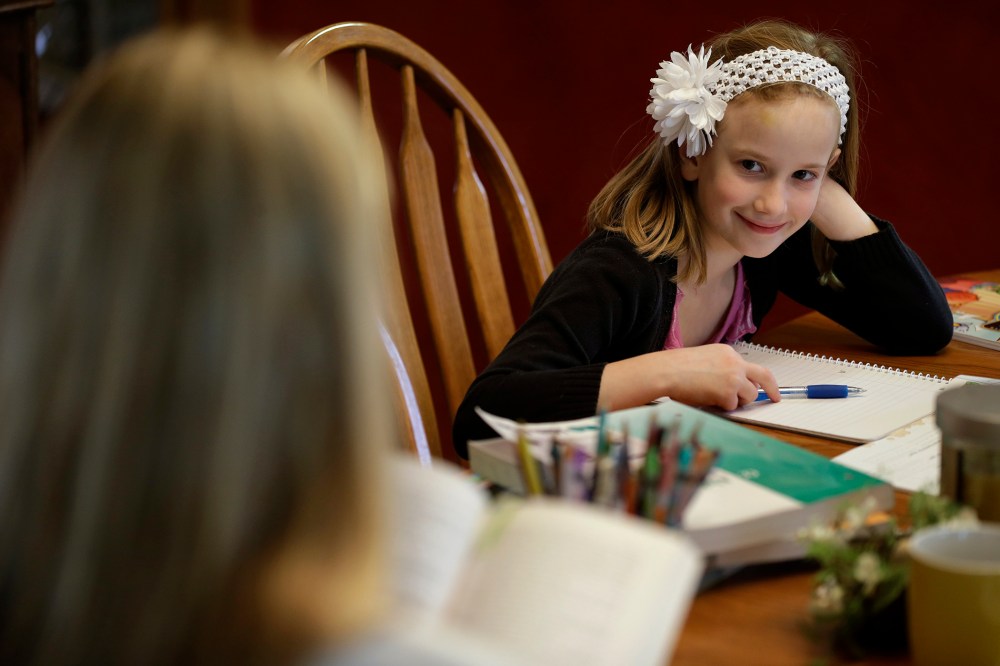 Abigail Gustoff listens to her mom Sara read while home schooling at the kitchen table in in their home in Des Moines, Ia., April 18, 2013. (Photo by Charlie Neibergall/AP)