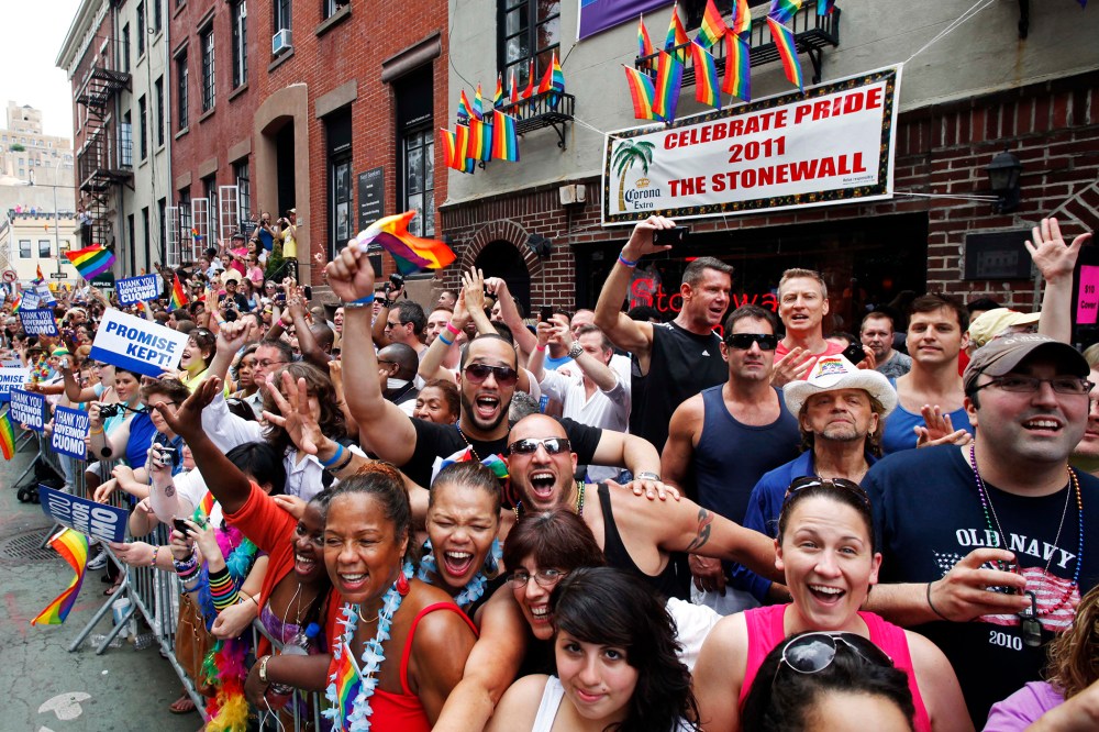 People cheer while standing in front of the Stonewall Inn on Christopher Street in Greenwich Village as the annual Gay Pride parade passes, June 26, 2011 in New York, N.Y. (Photo by Mark Lennihan/AP)