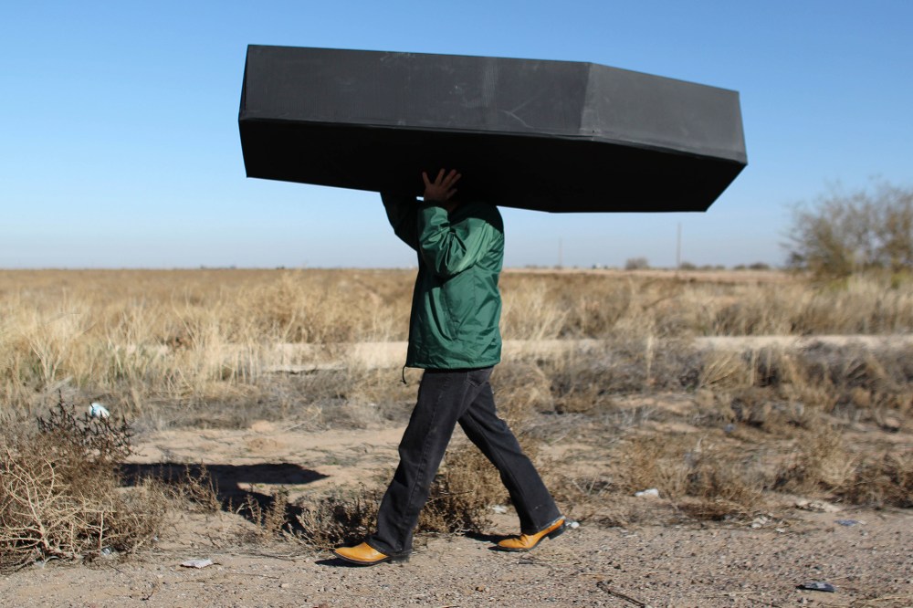 In this Jan. 20, 2016 file photo, a demonstrator carries a mock coffin, representing migrants who have died, outside the U.S. Immigration and Customs Enforcement detention center in Eloy, Ariz. (Photo by Ricardo Arduengo/AP)